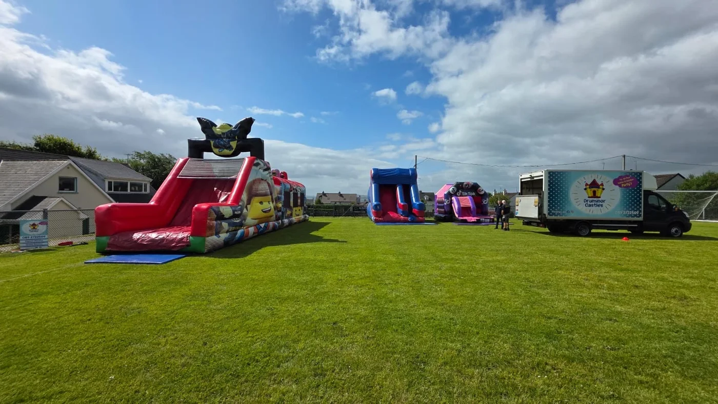 Several Druminor Castles inflatables set up on a field beside the branded van